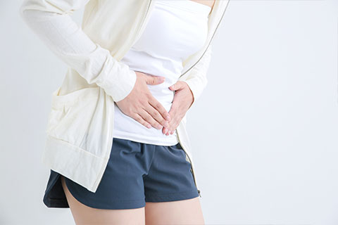 お腹を押さえる女性