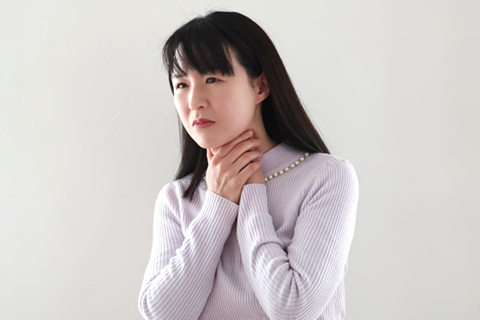 喉を抑える女性